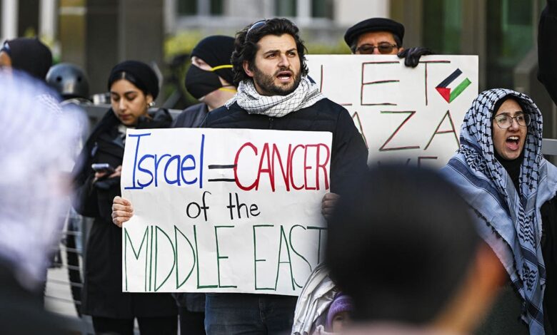 Anti-Israel protester with sign saying "Israel = Middle Eastern cancer"