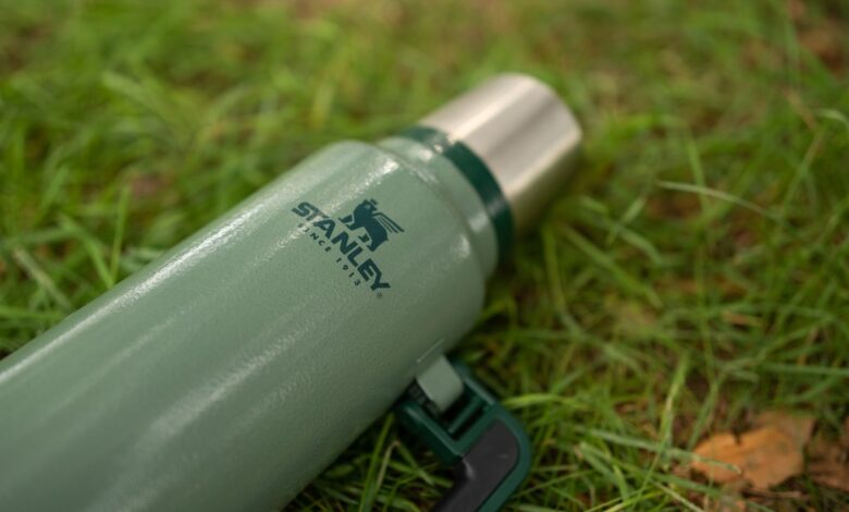 A green thermos Stanley on grass in Warsaw, Poland - August 20, 2023