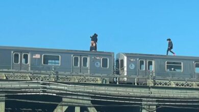 Man with exposed buttocks stands atop train car as another man walks toward him