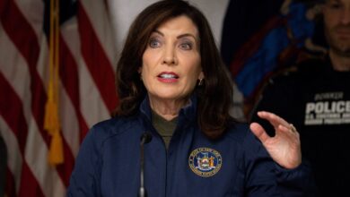 New York Governor Kathy Hochul speaking at a podium with a flag behind her after an incident at the Rainbow Bridge border crossing in Niagara Falls.