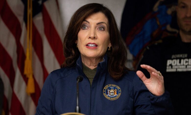 New York Governor Kathy Hochul speaking at a podium with a flag behind her after an incident at the Rainbow Bridge border crossing in Niagara Falls.