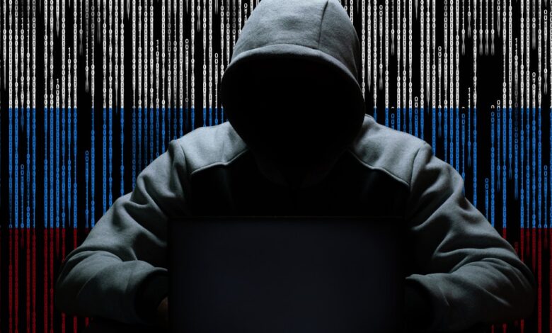 A hacker sitting with a hood against a backdrop of binary code.