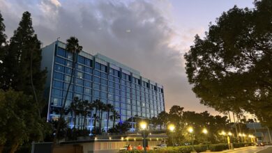 Exterior view of the Disneyland Hotel at twilight with illuminated windows and palm trees.