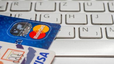 Close-up of a pile of Visa PayWave and MasterCard credit and debit cards on a laptop keyboard