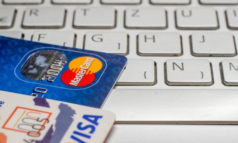 Close-up of a pile of Visa PayWave and MasterCard credit and debit cards on a laptop keyboard