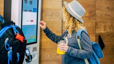 Woman make food order in modern display at fast food restaurant - self-service panel technology and people in travel lifestyle taking hamburger to eat