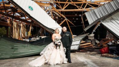 Kyle and Taylor on their wedding day standing in front of the damage at Brookdale Farms in Eureka, Missouri.