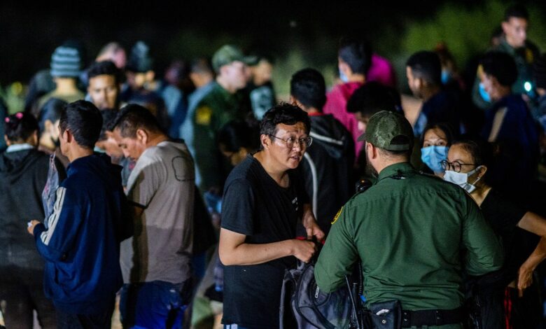 Chinese migrants speak to a border patrol officer before being processed