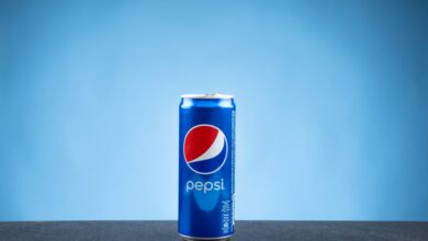 A can of Pepsi on a flat surface against a blue backdrop.