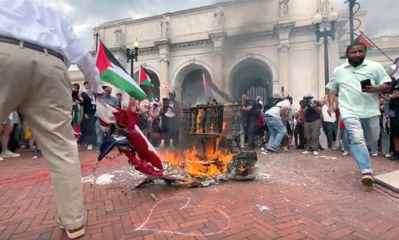 An unnamed patriot reaches down to rescue the American flag from being burned