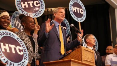 Bill de Blasio standing at a podium at a rally as the Hotel and Motel Trades Council union endorses him, with Chirlane McCray in the audience.