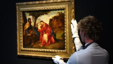 A Christie's art handler poses for a photograph alongside Titian's Rest on the Flight into Egypt masterpiece,