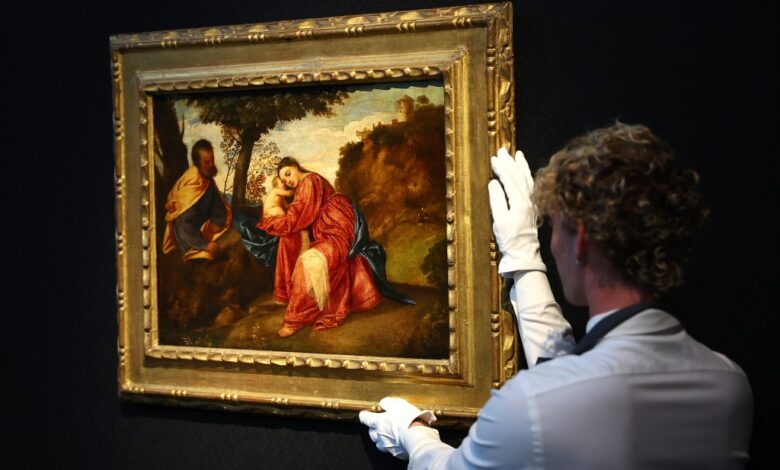 A Christie's art handler poses for a photograph alongside Titian's Rest on the Flight into Egypt masterpiece,