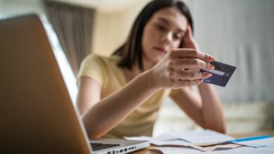 Distressed Asian woman feeling worried about financial troubles, looking at paperwork and bills in her home