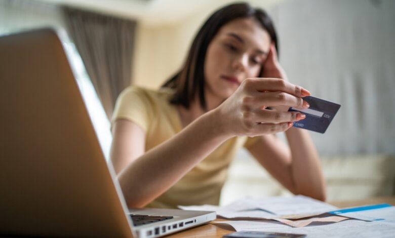 Distressed Asian woman feeling worried about financial troubles, looking at paperwork and bills in her home