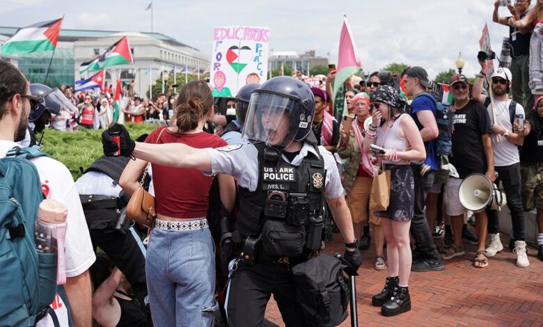 cop in riot gear with pepper spray confronts protester