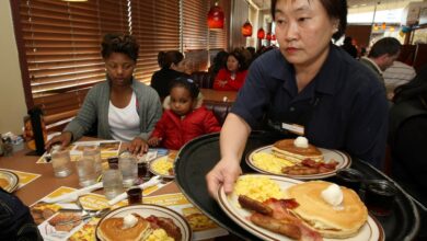 Woman serving breakfast to customers at a Denny's