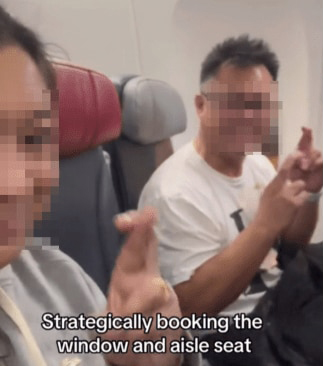 a couple with fingers crossed and middle seat between them on airplane