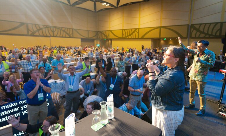 Worshipers in a conference meeting room sing and pray.