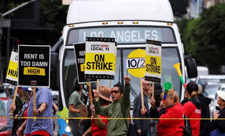 Hotel workers holding signs as they march and protest for their rights in Los Angeles, while a bus driver waits to cross the road, captured on October 25, 2023.