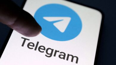 Finger pointing at the Telegram app logo on a cell phone screen