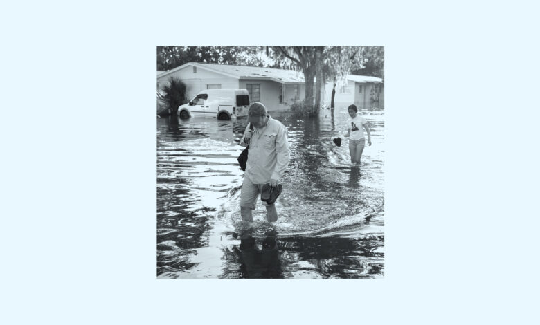 A man and woman walking through water left from the Hurricane Helene