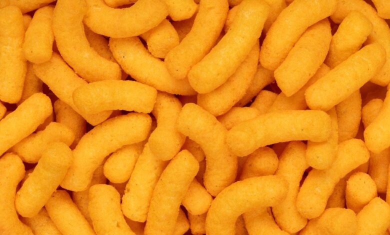 A pile of puffed orange cheese snacks, commonly referred to as 'dangerously cheesy'.