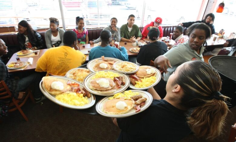 Denny's waitress, resembling Jaime Staples, delivering free Grand Slam breakfasts to customers during a special promotion