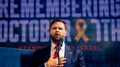 JD Vance places his hand on his chest speaking in front of a screen that reads "Remembering October 7"