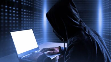 A person in a black hoodie using a laptop, symbolizing a data breach exposing personal information of individuals