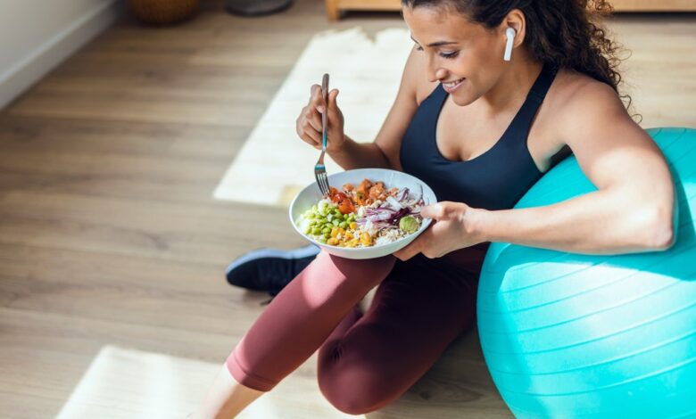 You don't have to spend a lot of money on the latest programs to get the best weight loss results. Here, a woman eats a healthy bowl of food while resting her arm on an exercise ball.
