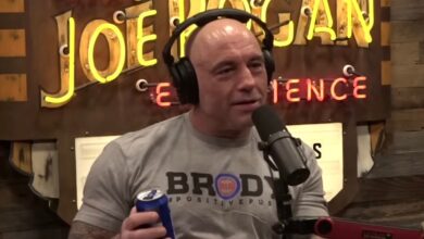 Joe Rogan wearing headphones, holding a can of Bud Light, in his podcast show