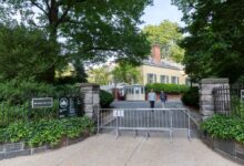 NYPD officers and barricades around Gracie Mansion in Yorkville, with people walking in the driveway during a socially distanced Black Lives Matter vigil.