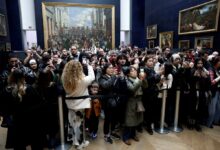 Tourists behind a security cordon photographing the Mona Lisa at the Louvre Museum, France