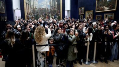 Tourists behind a security cordon photographing the Mona Lisa at the Louvre Museum, France