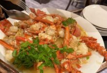 Woman looking upset at Canton Lane Chinese restaurant with a plate of seafood, including live lobster, on the table