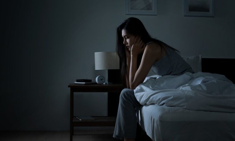 woman sitting on bed in the dark