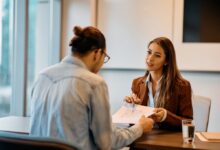 Young bank manager discussing an agreement with a client at an office table