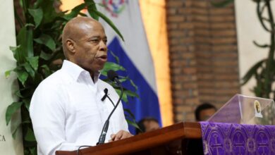 New York City Mayor Eric Adams speaking at a podium during a mass in Santo Domingo for the victims of a roof collapse