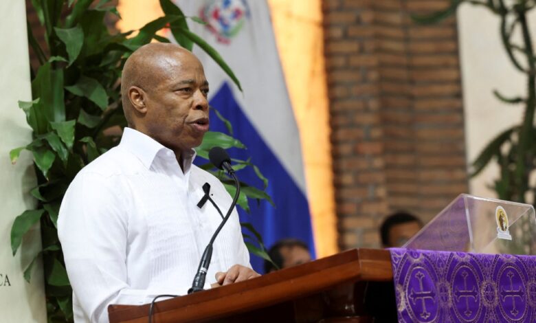 New York City Mayor Eric Adams speaking at a podium during a mass in Santo Domingo for the victims of a roof collapse