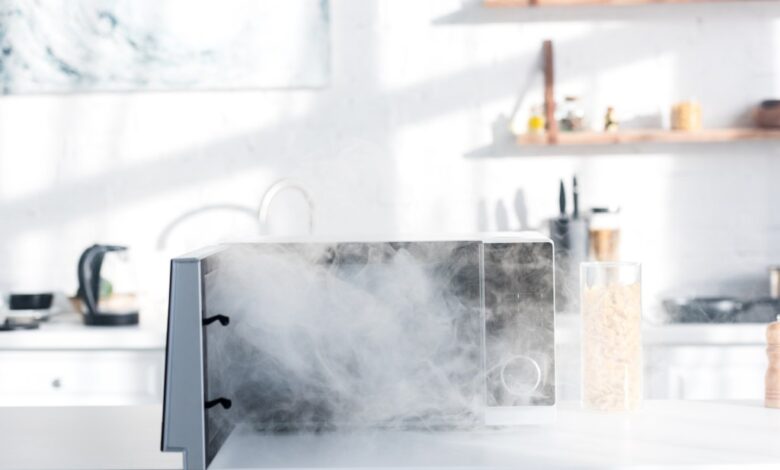 Broken and steamy microwave emitting smoke on a kitchen table