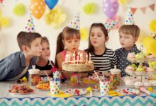 Group of joyful children blowing out candles on a birthday cake at a party