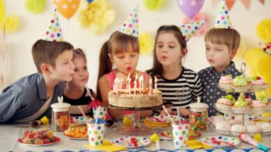 Group of joyful children blowing out candles on a birthday cake at a party