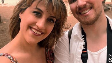 Couple smiling for a selfie in front of a cityscape.