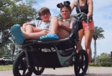 Woman pushing two children in a stroller at Disneyland.