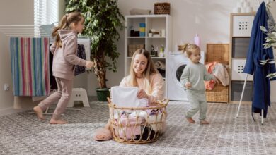 A mother sorts laundry in a basket while her two young daughters play nearby.