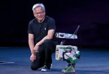 Jensen Huang kneeling next to a humanoid robot.