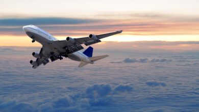 Airplane flying above clouds at sunset.