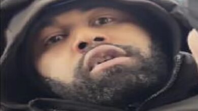 Close-up of a man with a beard and dark hooded jacket, identified as a person of interest by Crime Stoppers.