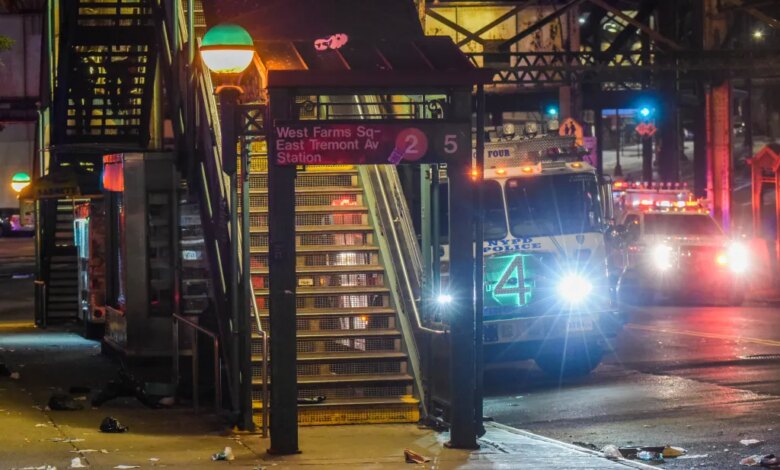 The entrance to West Farms Square-East Tremont Avenue train station at night, with an NYPD police truck and other emergency vehicles with flashing lights on the street in the background.